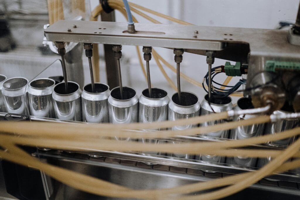 Close-up of automated machinery on a beverage can filling production line indoors.